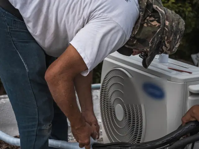 Technician working on an outdoor central air conditioner